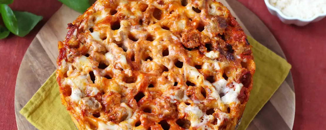 Pečen timballo iz rigatoni s klobaso, bešamelom in mozzarello